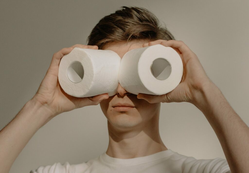 guy looking through two toilet rolls